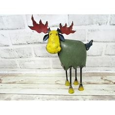 a metal moose with red and black antlers on it's head, standing in front of a brick wall