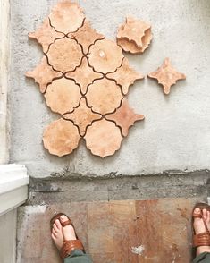 a person wearing sandals standing in front of a cement wall with tiles on it's side