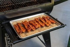 chicken wings are cooking on a grill with a griddle over the burner area