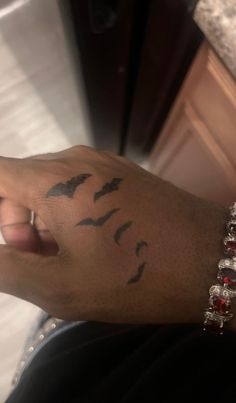 a person's arm with birds on it and a red beaded bracelet around the wrist