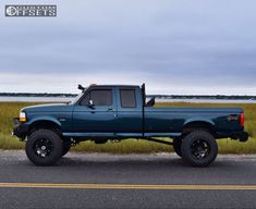 a blue pick up truck is parked on the side of the road near some grass