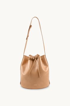 The Anne Leather Bucket Bag in almond is a stylish and versatile accessory that is perfect for any occasion. Crafted from soft 100% leather, this bag is both durable and luxurious. With its spacious interior and adjustable strap, it offers plenty of room for all your essentials while providing comfort and convenience. The almond color adds a touch of elegance to any outfit, making it a must-have accessory now and for many seasons to come.Made in Portugal.The nobility of leather is related to its Almond Color, Tiny Cottons, Outfit Making, Buckle Sandals, Leather Bucket Bag, Leather Bucket, Bucket Bag, 20 Cm, Adjustable Straps