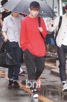 two boys walking down the street with umbrellas over their heads and one boy holding an umbrella