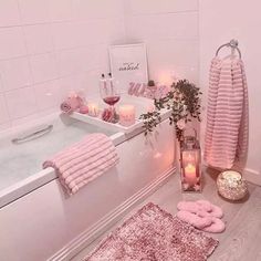 a bathroom with pink towels and candles on the counter next to bath mats, rugs and other items