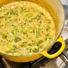 a pot filled with broccoli and cheese on top of a gas stovetop