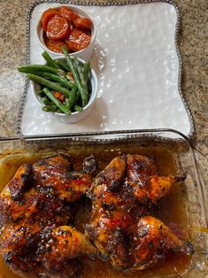 two trays filled with meat and vegetables next to a bowl of green beans on a table