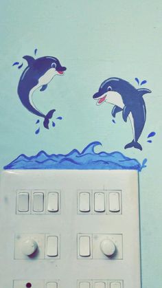 two dolphins jumping out of the water on top of a white wall mounted light switch