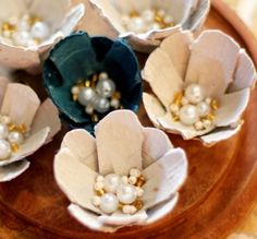 four paper flowers with pearls in them sitting on a wooden platter, ready to be used as centerpieces