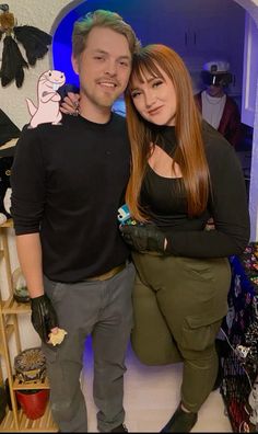 a man and woman standing next to each other in front of a wall with decorations