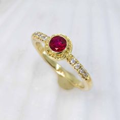 Treat yourself to an exquisite adornment handcrafted in 18K granulated gold, showcasing a stunning ruby and glittering diamonds, to add a hint of sophistication and charm to any outfit. The classic simplicity of this Ruby & Diamond Classical Ring will add an elegant allure to your jewelry collection. Featuring a dazzling 0.58ct ruby accented with 0.1cttw of 1.5mm VS/GH diamonds. Size 6, but each ring comes with free sizing and FREE SHIPPING! Watch a video of this ring being made HERE Unsure what Ruby Ring With Diamond Pavé Setting, Ruby Ring With Pave Setting And Diamond, Formal Yellow Gold Ruby Ring With Pave Setting, Ruby Rings With Pave Setting, Ruby Rings With Single Cut Diamonds, Elegant Yellow Gold Ruby Ring With Pave Setting, Gold Ruby Jewelry With Pave Setting, Ruby Rings With Round Cut Single Diamonds, Fine Jewelry Yellow Gold Ruby Ring With Halo Setting