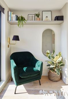 a green chair sitting in front of a mirror next to a potted plant