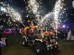 two people riding on the back of a four wheeled vehicle with fireworks in the background