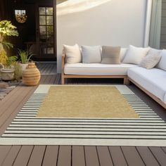 a white couch sitting on top of a wooden floor next to a brown and white rug