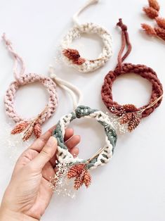 four different types of bracelets with pinecones on them, one being held by a person's hand