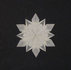 an origami snowflake is shown on a black surface with white lines