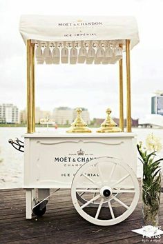 an ice cream cart is on the dock by the water and has gold cups in it