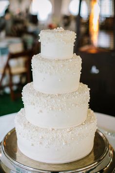 a three tiered white wedding cake sitting on top of a table