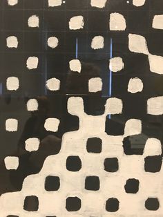 an abstract painting with white squares and black dots on a black background, in front of a window