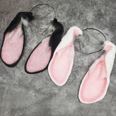 three pairs of pink and black bunny ears with long tails on a gray surface next to one another