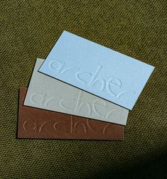 three business cards sitting on top of a green chair next to a brown and blue piece of paper