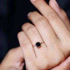 a woman's hand with a black diamond ring on her left and right hand