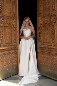 a woman in a white wedding dress is standing at the entrance to an ornate wooden door