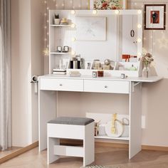 a white vanity table with lights on the wall above it and a stool in front of it