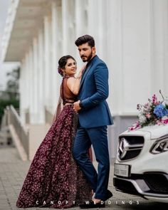 a man and woman standing next to each other in front of a white mercedes car