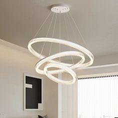 a modern chandelier hanging from the ceiling in a living room with white walls