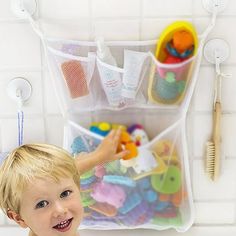 a little boy standing in front of a bath tub filled with lots of toy items