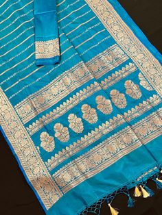 SILK MARK CERTIFIED !!Gorgeous Pure Katan Turquoise Color with undertone of Blue with Copper and Slier Zari Work. Strips Sarees in Copper and Sliver Zari with Floral Buttas on the Pallu Soft, light weight and easy to drape Saree. The Strips are dense towards the pallu and get scattered the other end. Item : SareeColor : Turquoise Color with undertone of BlueBase Fabric : Pure Katan Silk Blouse piece : Comes with Blouse pieceBlouse material : Pure Katan SilkFall & Edging (Yes/No) : YesComes with Turquoise Cutdana Sets, Traditional Turquoise Wear With Zari Weaving, Traditional Turquoise Saree With Zari Weaving, Turquoise Handloom Saree For Festivals, Turquoise Banarasi Silk Traditional Wear, Turquoise Traditional Wear With Zari Weaving, Turquoise Traditional Wear With Zari Weaving For Festivals, Turquoise Traditional Wear With Zari Work For Festivals, Traditional Turquoise Saree For Festive Occasions