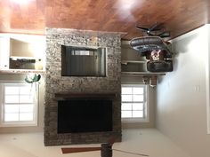 a living room with a stone fireplace and ceiling fan