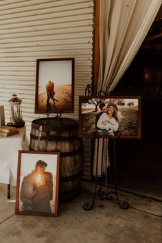 two framed pictures sitting on top of a barrel next to a table with white cloth