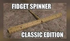 a wooden ruler laying on the ground with text that reads, fidget spiner classic edition