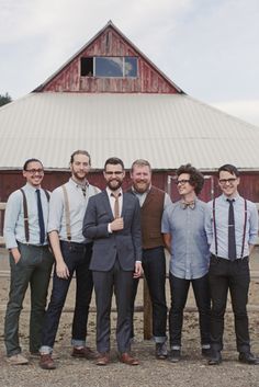 a group of men standing next to each other in front of a barn