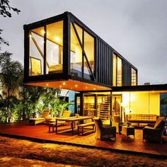 a house made out of shipping containers on top of a wooden deck in the evening