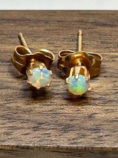 This is a pair of genuine, vintage, natural, 14K yellow gold and opals stud earrings that are a minimalist design.  The dainty earrings feature the natural, genuine round-cut, prong -set opal stones set in 14K yellow gold bezels. The opals have pretty pinks, blues and other colors, especially when the light hits them. The earrings measure about 1/8" in diameter. Their posts are about 3/8" in length. The earrings are stamped 14K and weigh less than 1 gram. They also have been tested and are genui Classic Opal Jewelry For Gifts, Classic Opal Jewelry As A Gift, Classic Opal Birthstone Jewelry, Opal Jewelry In Yellow Gold With Matching Earrings, Yellow Gold Opal Jewelry With Matching Earrings, Yellow Gold Opal Earrings Gift, Opal Yellow Gold Earrings For Gifts, Yellow Gold Opal Earrings For Gifts, Minimalist 14k Stamped Earrings For Gift