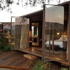 a wooden deck leading to a bedroom with a bed in the back and patio area next to it