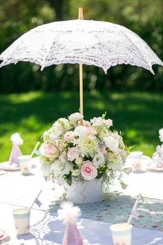 an umbrella that is on top of a table with flowers and other items around it