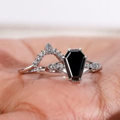 a close up of a person's hand holding an engagement ring with a black stone