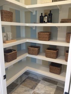 an empty pantry with baskets and bottles on the shelves