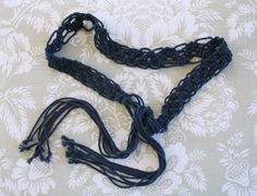 a black crocheted necklace with tassels on a white and blue background