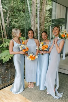 the bridesmaids are all laughing together in their blue gowns and bouquets