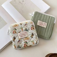 two small purses sitting on top of a table next to an open drawing book