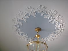 an ornate white and gold wall hanging in the corner of a room with a chandelier