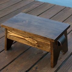 a small wooden bench sitting on top of a wooden floor next to a body of water