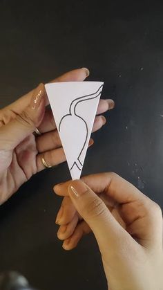 two hands are holding an origami piece