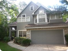 a gray house with two garages and trees in the background