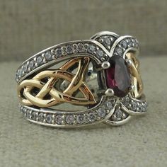 Celtic Knot Ring in Sterling Silver with 10K Gold White Topaz Trim & Rhodolite or Iolite Gem. 13 mm at widest point tapers to 3 mm Gem: Oval 6 mm long 5 mm wide Size 5 to 11 Stamped .925 & 10K Nicely boxed with silver cloth. Rhodolite is Red Iolite is Blue/Purple Spinner Rings Womens, Celtic Knot Wedding Ring, Celtic Knot Wedding, Celtic Wedding Bands, Heart Wedding Rings, Celtic Ring, Celtic Knot Ring, Rings Women, Celtic Wedding Rings