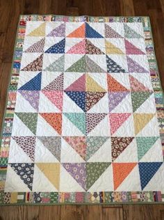 a multicolored quilt is laying on the floor next to a brown wooden floor